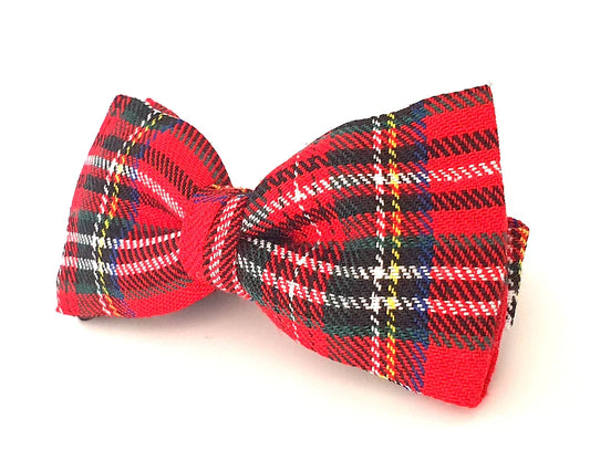 Pajarita de tela con diseño tartán rojo, negro, blanco y azul sobre fondo blanco