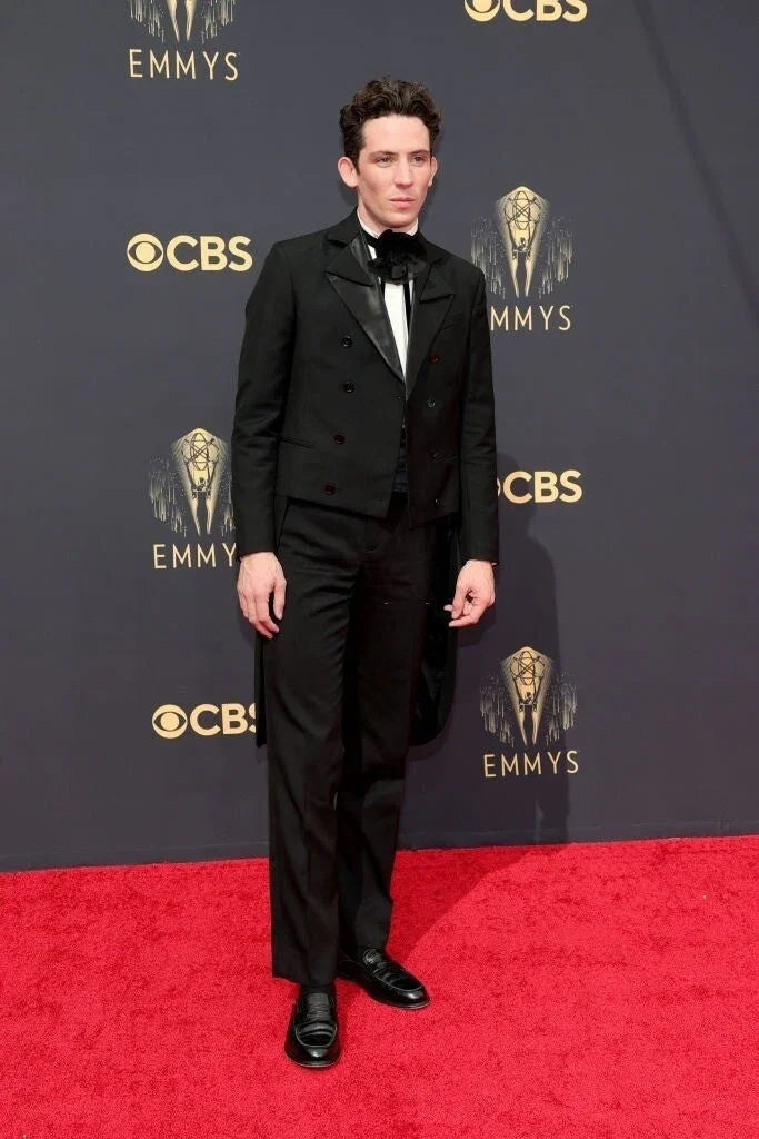Hombre elegante en la alfombra roja de los Emmy con traje negro y pajarita negra original.