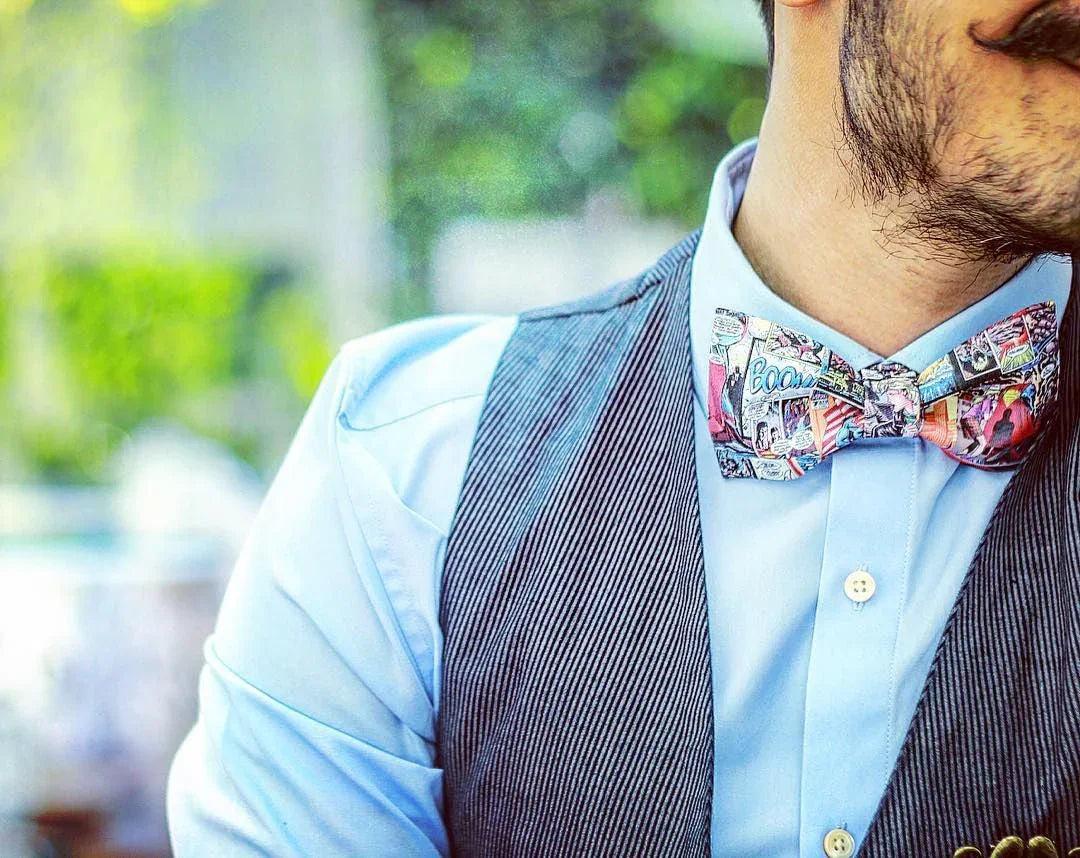 Hombre con camisa azul, chaleco gris y pajarita original con estampado de cómic, complementos frikis