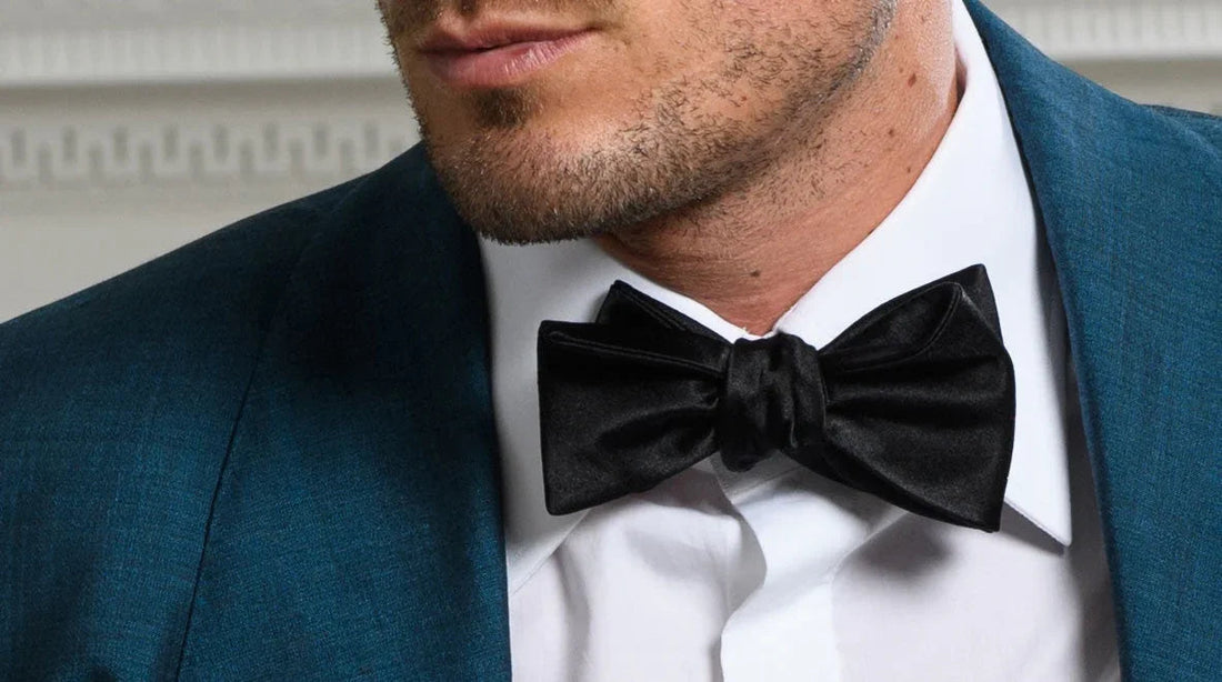 Hombre con pajarita negra de satén y camisa blanca, chaqueta azul elegante para evento formal
