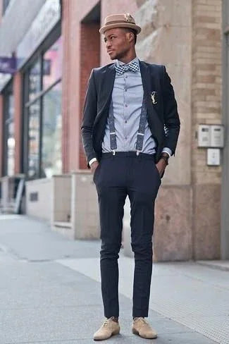 Hombre con pajarita de estampado vichy azul y blanco, traje oscuro, tirantes y sombrero beige en calle urbana